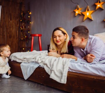 Mom dad smile little girl lying bed 360x320
